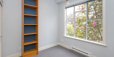 Bright room featuring large windows, a built-in bookshelf, and views of vibrant landscaping. Perfect for a study or guest space.