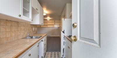 Spacious kitchen with ample cabinetry and tile countertops, leading into an inviting, open living space.