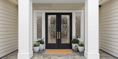 Inviting entrance featuring decorative beveled glass doors, vibrant planters, and a tasteful stone pathway, perfect for welcoming guests.