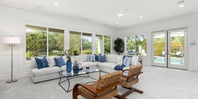 Spacious living area with large windows, offering abundant natural light and direct views of the pool.