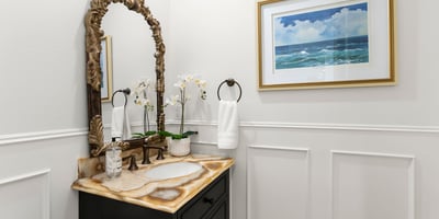 Downstairs Guest Bath-This inviting bathroom features a unique stone vanity , custom wainscoting and coastal-themed artwork, enhancing its modern appeal.