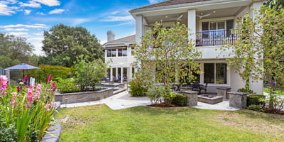 Spacious home with lush gardens, multiple outdoor seating areas, and a beautifully landscaped yard for relaxation.