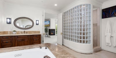 Primary Bathroom-Luxurious bathroom featuring a jetted tub, modern glass block shower, and ample natural light.