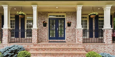 Welcoming entrance features a brick facade, dual blue doors, and attractive landscaping for a polished look.