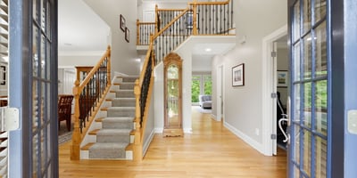 Bright and inviting entryway featuring a spacious layout, hardwood floors, and a sweeping staircase.