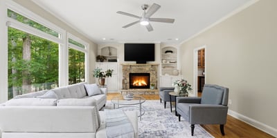 Bright and inviting living space featuring large windows, a cozy fireplace, and modern furnishings.