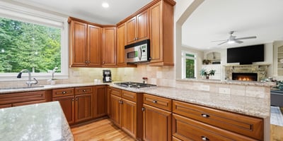 This spacious kitchen features rich cabinetry, granite countertops, and ample natural light, perfect for culinary enthusiasts.