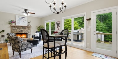 Spacious living area features a cozy fireplace and direct access to a private deck surrounded by greenery.