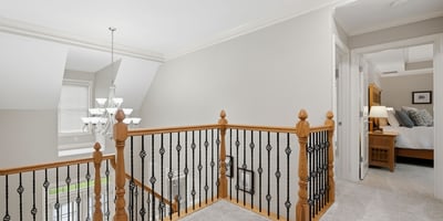 This spacious second-floor landing features a modern chandelier and leads to cozy, well-lit bedrooms.