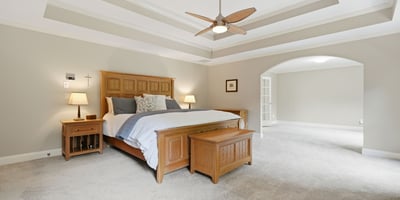 Spacious master bedroom with tray ceiling, abundant natural light, and an adjoining versatile living area.
