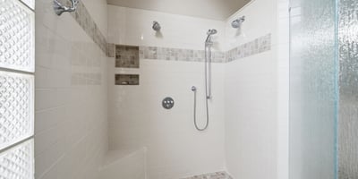 Spacious, modern shower with multiple showerheads and built-in shelving, ideal for a refreshing experience.