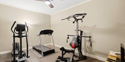 Spacious workout room featuring modern fitness equipment and ample natural light, perfect for home exercise routines.