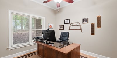 Bright home office featuring a spacious desk, ample natural light, and a tasteful decor theme.