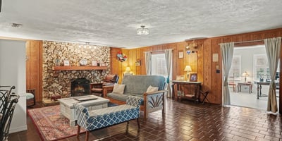 Living Room with large river rock, wood burning fireplace and gorgeous pecky cypress accent walls!