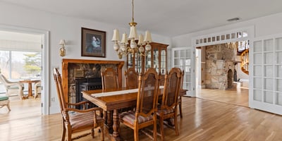 Spacious dining area features a classic table set, surrounded by natural light and detailed woodwork throughout.