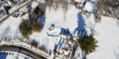 Stunning aerial view of a winter landscape featuring a spacious property amidst a pristine snowy backdrop.