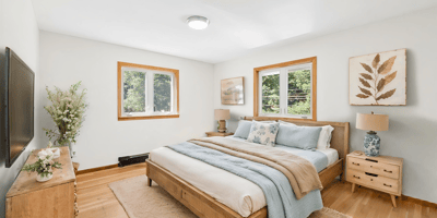 Bright and inviting bedroom featuring large windows, natural wood accents, and modern furnishings for comfort.