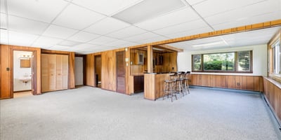Spacious, versatile recreation area featuring a built-in bar and ample natural light from large windows.