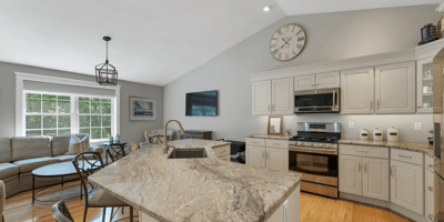 Modern kitchen featuring high ceilings, granite countertops, and spacious living area with abundant natural light.