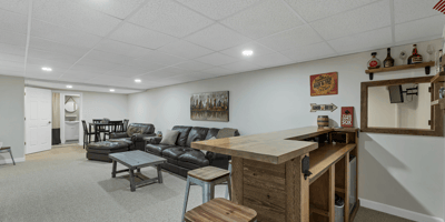 Spacious lower-level entertainment area featuring a bar, cozy seating, and ample space for gatherings.