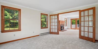 Spacious living area with abundant natural light, featuring French doors and a cozy fireplace for gatherings.