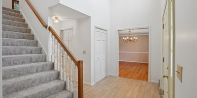 Spacious entryway with a graceful staircase leads to a versatile living area and abundant natural light.
