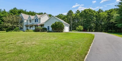 Spacious home on a large lot, surrounded by lush greenery and featuring ample parking options.