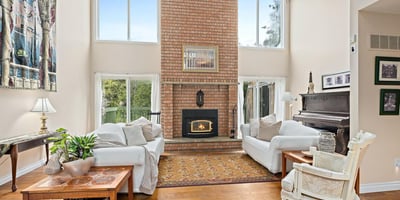 Bright, inviting living space features a striking brick fireplace and large windows, perfect for relaxed gatherings.