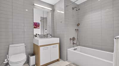 Modern bathroom featuring sleek tile design, a spacious vanity, and a combined shower-tub setup.