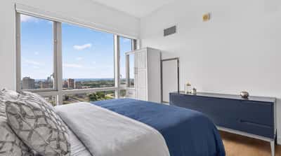 Bright, modern bedroom featuring expansive windows with stunning urban views and minimalist design.