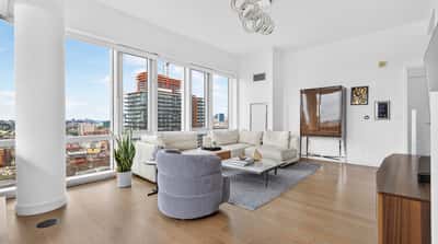Bright and spacious living area featuring large windows with expansive city views and modern furnishings.