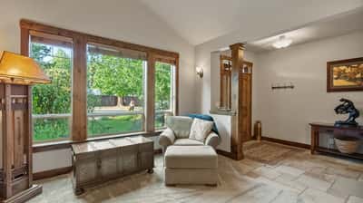 Bright and inviting entryway featuring large windows, natural light, and a cozy seating area.