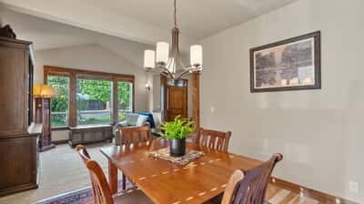 Bright dining area featuring a wooden table, large windows, and a direct view of the backyard.