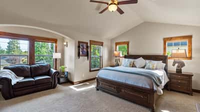 Spacious master bedroom featuring large windows, ample natural light, and a cozy seating area for relaxation.