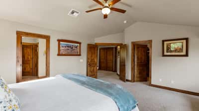 Spacious bedroom featuring vaulted ceilings, natural light, and quality wood accents throughout for a warm atmosphere.