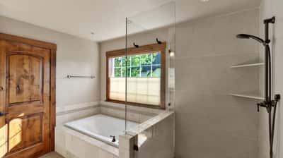 Discover this modern bathroom featuring a glass-enclosed shower, soaking tub, and natural light. Ideal for relaxation.
