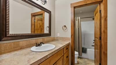 Bright bathroom featuring a spacious countertop, ample storage, and a combination tub/shower for convenience.