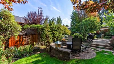 Lush backyard retreat featuring a brick patio, diverse landscaping, and ample space for relaxation and gatherings.