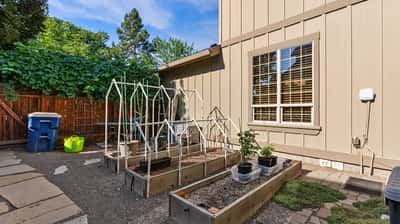 Discover a functional outdoor space featuring raised garden beds and a greenhouse, perfect for gardening enthusiasts.