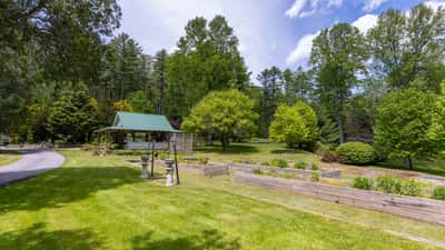 Spacious outdoor area featuring a lush garden, shaded gazebo, and scenic views of surrounding nature.