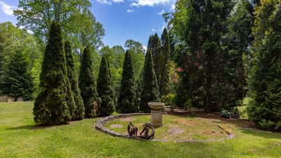 This expansive outdoor space features lush greenery and a unique stone birdbath, perfect for relaxation.