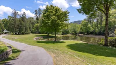 Spacious lot with scenic pond views, lush greenery, and well-maintained pathways, perfect for outdoor activities.