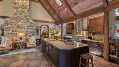 This spacious kitchen features a striking stone fireplace, high ceilings, and a large island for gatherings.