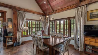 Inviting dining area featuring large windows, rustic beams, and ample space for gatherings or entertaining.