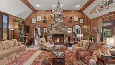 Spacious living area features a stone fireplace, wood paneling, and panoramic windows for natural light.