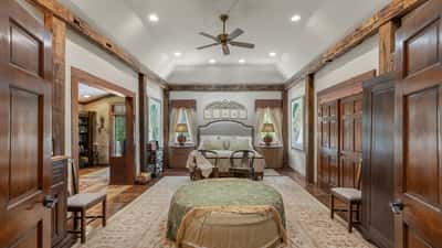 Spacious bedroom featuring rustic beams, large windows, and inviting seating, perfect for relaxation and comfort.