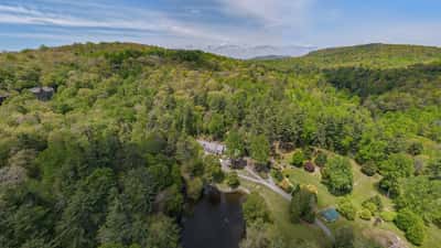Nestled among lush greenery, this expansive property features a tranquil pond and scenic mountain views.
