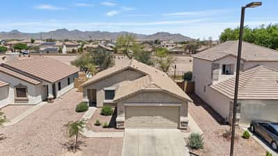 Attractive front elevation featuring low-maintenance landscaping, an attached two-car garage, and scenic White Tank Mountain views. Enjoy added privacy with no neighbors behind in this desirable Buckeye neighborhood.