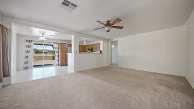 Spacious living room offers neutral finishes, plush carpet, ceiling fan, and a bright open layout ready for your personal design. The seamless flow enhances both comfort and functionality.