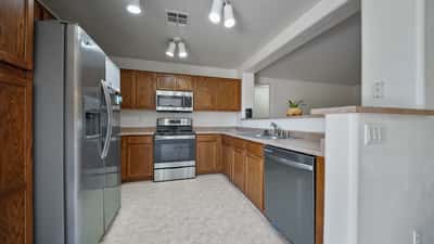Functional kitchen includes abundant cabinetry, stainless steel appliances, generous counter space, and a breakfast bar that opens to the living area, creating a practical layout for cooking and entertaining.